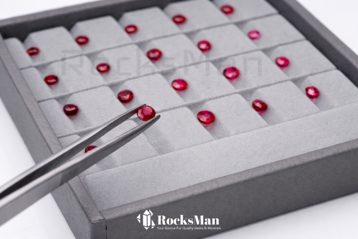 natural ruby collection with tweezers selecting a gemstone on gray tray
